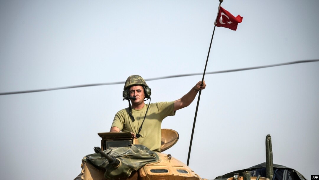 Seorang tentara Turki mengendarai tank di perbatasan Turki dengan Suriah. 