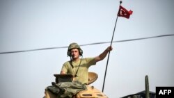 FILE - A soldier gestures as Turkish Army tanks drive to the Syrian-Turkish border town of Jarabulus, Aug. 25, 2016.