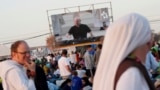 FILE - Roman Catholic priest Guilherme Peixoto, on video screen, plays techno music to help pilgrims wake up at Parque Tejo in Lisbon on Aug. 6, 2023, where Pope Francis will preside over a mass celebrating the 37th World Youth Day later in the day. (AP Photo/Ana Brigida)