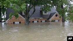 A home is shown as floodwaters from Tropical Storm Harvey rise, Aug. 28, 2017, in Spring, Texas.