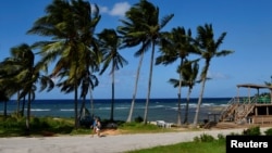 People walk near a Playa Baracoa, Cuba, beach as Tropical Storm Rafael approaches, Nov. 4, 2024. 