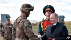 Presiden Rusia Vladimir Putin (kanan), memberi penghargaan kepada tentara Cina di tempat pelatihan "Tsugol", sekitar 250 kilometer tenggara kota Chita di Siberia Timur, Rusia, saat meninjau latihan militer Vostok 2018, Kamis, 13 September 2018.