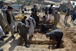 FILE - Shi'ite mourners and relatives dig graves the day after multiple blasts hit outside a girls' school, during the burial at a desolate hilltop cemetery in Dasht-e-Barchi on the outskirts of Kabul, May 9, 2021.
