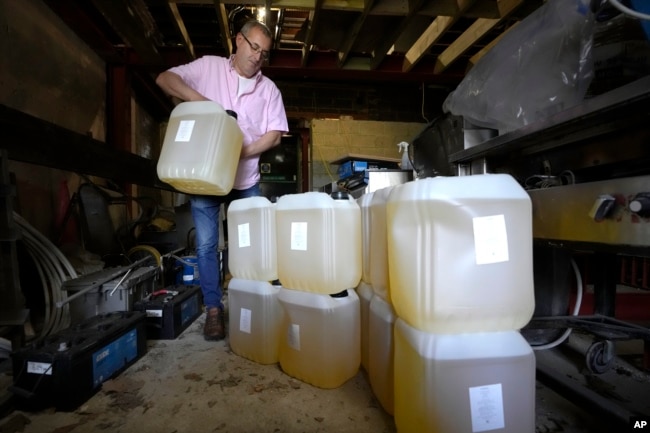 FILE - Harry Niazi carries a container of sunflower oil out of storage at Olleys Fish Experience in Herne Hill in London, Thursday, April 21, 2022. (AP Photo/Kirsty Wigglesworth)