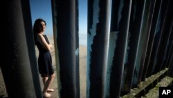 Liz Prado posa para una foto en Tijuana, México, el 23 de abril de 2020, vista a través de la estructura fronteriza que separa México de Estados Unidos.