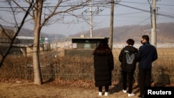2021年2月12日，在南韓農曆新年到來之際，一名脫北者和他的孩子們站在京畿道坡州市非軍事區附近的鐵絲網前。（路透社）