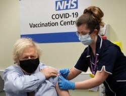 FILE - Britain's Prime Minister Boris Johnson receives the first dose of the AstraZeneca vaccine administered by nurse and Clinical Pod Lead, Lily Harrington at St.Thomas' Hospital in London, March 19, 2021.