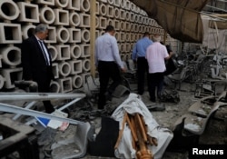 Egyptian investigators are seen in front of the damaged facade of the National Cancer Institute after an overnight fire from a blast, in Cairo, Egypt Aug. 5, 2019.