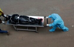 Hospital staff carry the body of a person who died of COVID-19 to a morgue in Mumbai, India, May 29, 2020.