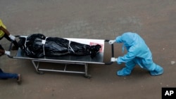 Hospital staff carry the body of a person who died of COVID-19 to a morgue in Mumbai, India, May 29, 2020.
