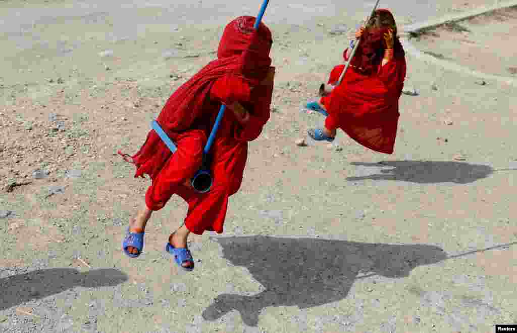 Girls ride on swings during the first day of the Muslim holiday of the Eid al-Adha, in Kabul, Afghanistan, Aug. 11, 2019.