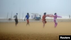 Women shield their faces during strong winds at Marina beach in Chennai, southern India, Oct. 31, 2012.