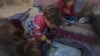 Girls in the Eid family eat lentils cooked by their mother, Yasmin, at their tent in a refugee camp in Deir al-Balah, Gaza Strip, Nov. 19, 2024. 