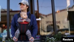 FILE - Steve Caniglia holds his six-month-old son, Boden, in San Francisco, California, Feb. 19, 2014. 