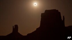 FILE - The new moon crosses in front of the sun creating an annular eclipse over West Mitten, left, and East Mitten buttes in Monument Valley, Arizona, May 20, 2012.