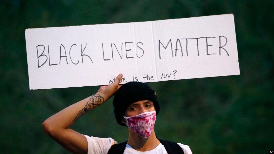 A protester holds up a sign in front of City Hall, May 30, in Phoenix, protesting the death of George Floyd.