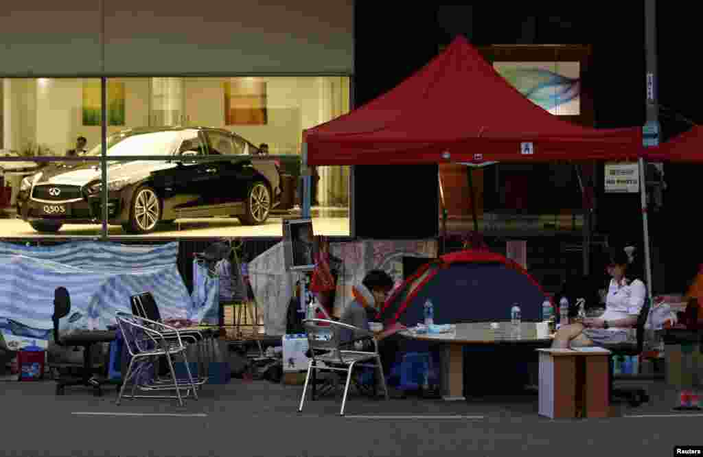 Pemrotes pro-demokrasi duduk di jalanan,&nbsp;depan sebuah ruang pamer mobil di pusat distrik keuangan Hong Kong, 6 November 2014. 