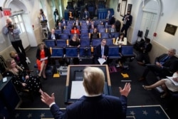 FILE - Reporters are seen complying with social distancing rules as President Donald Trump speaks about the coronavirus in the James Brady Press Briefing Room at the White House, in Washington, April 13, 2020.