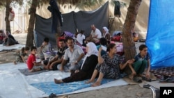 FILE - Displaced Iraqis from the Yazidi community gather at a park near the Turkey-Iraq border at the Ibrahim al-Khalil crossing, as they try to cross to Turkey, in Zakho, 475 km northwest of Baghdad, Aug. 15, 2014.