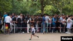 Newly arrived migrants wait in front of the State Office for Health and Social Affairs to apply for asylum in Berlin, Germany, Aug. 11, 2015.