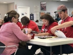 Deirdre Felgar reviews her identification cards with polling officials before getting her ballot to vote, in Las Vegas, Nevada. (Carolyn Presutti/VOA)