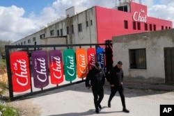 FILE - Employees walk out of the bottling plant of the Chat Cola Company in the West Bank city of Salfit, Feb. 13, 2025.