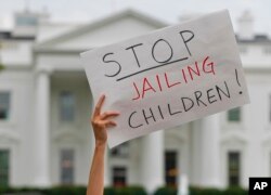 FILE —A demonstrator holds up a sign during a rally opposed to President Trump's family separation policy, in front of the White House in Washington, June 21, 2018.