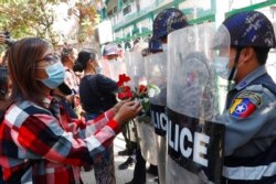 Supporters give roses to police while four arrested activists make a court appearance in Mandalay, Myanmar, Feb. 5, 2021.