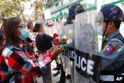Supporters give roses to police while four arrested activists make a court appearance in Mandalay, Myanmar, Feb. 5, 2021.