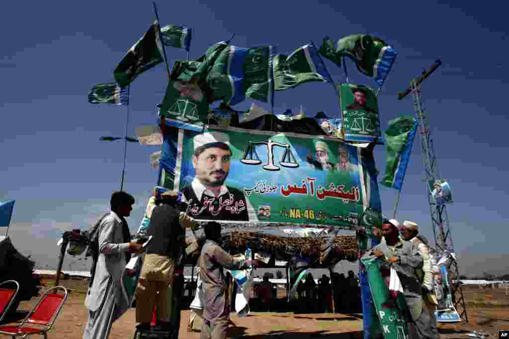 Supporters of Pakistan's religious political party Jamaat-e-Islami hang campaign banners in the Jalozai camp in Peshawar, Pakistan, May 8, 2013.