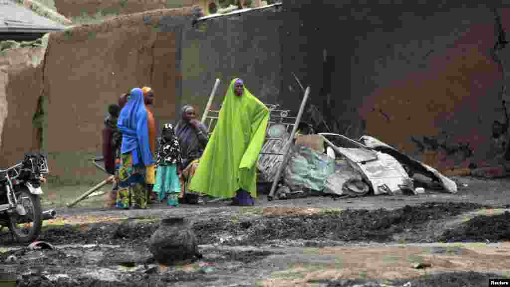 Women and children gather near burnt houses and ashes in the aftermath of what Nigerian authorities said was heavy fighting between security forces and Islamist militants in Baga