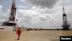 Archivo. Un trabajador de un campo petrolero camina junto a las plataformas de perforación en un pozo petrolero operado por la petrolera estatal venezolana PDVSA, en la rica franja petrolera del Orinoco, el 16 de abril de 2015.