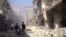 In this photo taken from video obtained from the Shaam News Network, which has been authenticated based on its contents and other AP reporting, Syrian men run to aid injured people in the aftermath of a strike by Syrian government warplanes on a residenti