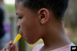 Zariah Fields memakan es loli, 20 Juni 2024, di YMCA Camp Kern di Oregonia, Ohio. (Foto: AP/Joshua A. Bickel)