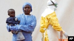 Mwamini Kahindo, an Ebola survivor working as a caregiver to babies who are confirmed Ebola cases, holds an infant outside the red zone at the Ebola treatment center in Butembo, Democratic Republic of Congo, March 25, 2019.