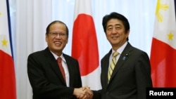 Presiden Filipina Benigno Aquino berjabat tangan dengan PM Jepang Shinzo Abe (kanan) di rumah din as PM Jepang di Tokyo (24/6).