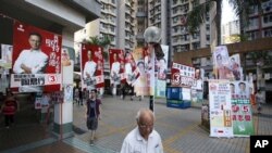 香港市民星期日穿越香港立法會選舉競選海報前往投票站