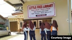 Lima siswi melihat-lihat buku di Little Free Library yang dipasang di teras rumah seorang guru di desa Rawajaya, kabupaten Cilacap. Courtesy Ari Hendra Permana