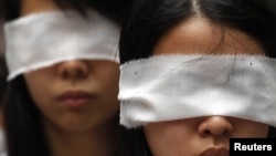 Protesters cover their eyes with white ribbons to symbolize mourning, as a protest to urge the Chinese authorities to carry out a proper investigation into the death of dissident Li Wangyang in Hong Kong June 10, 2012. 