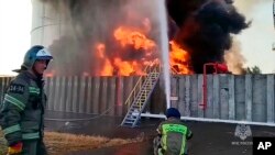 En esta fotografía tomada de un video publicado por el Servicio de Prensa del Ministerio de Emergencias de Rusia el martes 18 de junio de 2024, los bomberos trabajan en el sitio de un depósito de petróleo en el distrito de Azov de la región de Rostov del Don de Rusia.