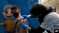 FILE - An Israeli man receives a booster shot of the coronavirus vaccine from a medical professional with Clalit Health Services at the Cinema City complex in Jerusalem, Aug. 30, 2021.