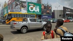 Des écoliers sont devant un panneau de campagne en faveur du "oui" avant le référendum constitutionnel à Abidjan, Côte d'Ivoire, le 27 octobre 2016. 