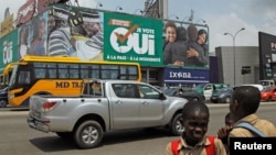 School children stand in front of a campaign billboard ahead of the referendum for a new constitution in Abidjan, Ivory Coast, Oct. 27, 2016. The billboard reads "I vote yes to peace and modernity." 