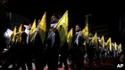 FILE - Hezbollah fighters march at a May 31, 2019, rally in a Beirut suburb. As Lebanon sinks deeper into poverty and collapse, many openly criticize the Iran-backed group, blaming it for its role in the multiple crises plaguing the country.