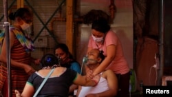 Manisha Bashu, right, and her mother press the chest of her father, who was receiving oxygen support at a Sikh temple amid the spread of coronavirus disease, in Ghaziabad, India, April 30, 2021. 