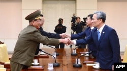 တောင်ကိုရီးယားသမ္မတရဲ့ လုံခြုံရေးဆိုင်ရာအကြံပေး Kim Kwan-Jin (ယာ) နဲ့ မြောက်ကိုရီးယား စစ်ဘက်ဆိုင်ရာ နိုင်ငံရေးအရာရှိ Hwang Pyong-So (ဝဲ) တို့ လက်ဆွဲနှုတ်ဆက်စဉ်။ (သြဂုတ်လ ၂၂၊ ၂၀၁၅)