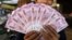 FILE - An Indian man displays new currency notes of 2000 Indian rupee in Ahmadabad, India, Nov. 11, 2016. 
