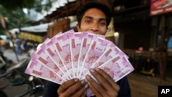 FILE - An Indian man displays new currency notes of 2000 Indian rupee in Ahmadabad, India, Nov. 11, 2016. The sudden withdrawal of 86 percent of India's currency has left cash in short supply, retail sales stumbling and wholesale markets in turmoil.