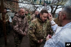 Vojni kapelan Jurij iz 24. mehanizovane brigade blagosilja ukrajinske vojnike tokom Božića u blizini grada Časiv Jar, Donjecka oblast, Ukrajina, srijeda 25. decembra 2024. (AP foto/Evgenij Maloletka)