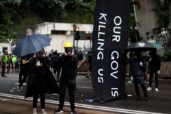 Masked protesters hold umbrellas during an anti-government rally in central Hong Kong, Oct. 6, 2019.